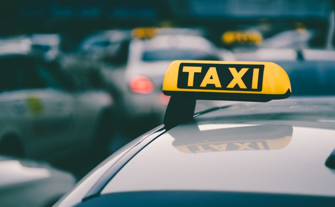 Selective focus shot of a yellow taxi sign in a traffic jam