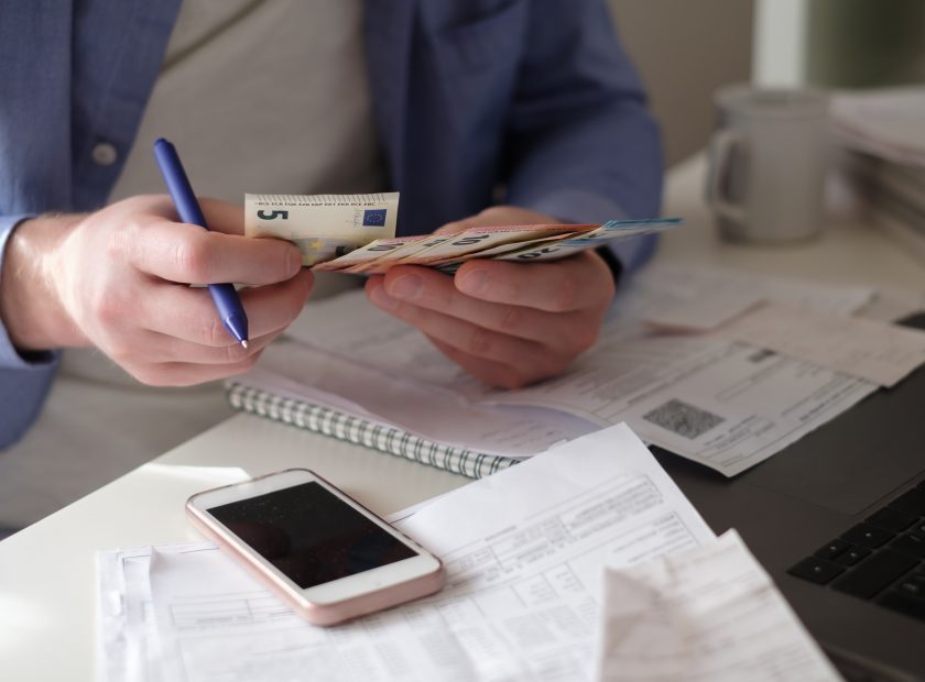 Caucasian man counting money sitting at home on his working table