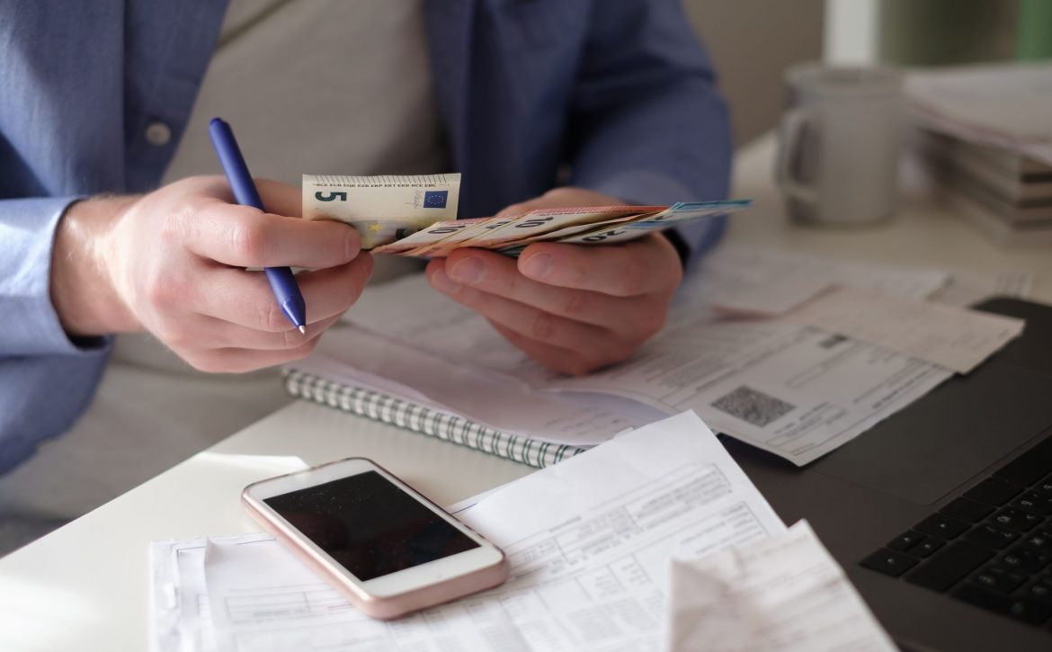 Caucasian man counting money sitting at home on his working table